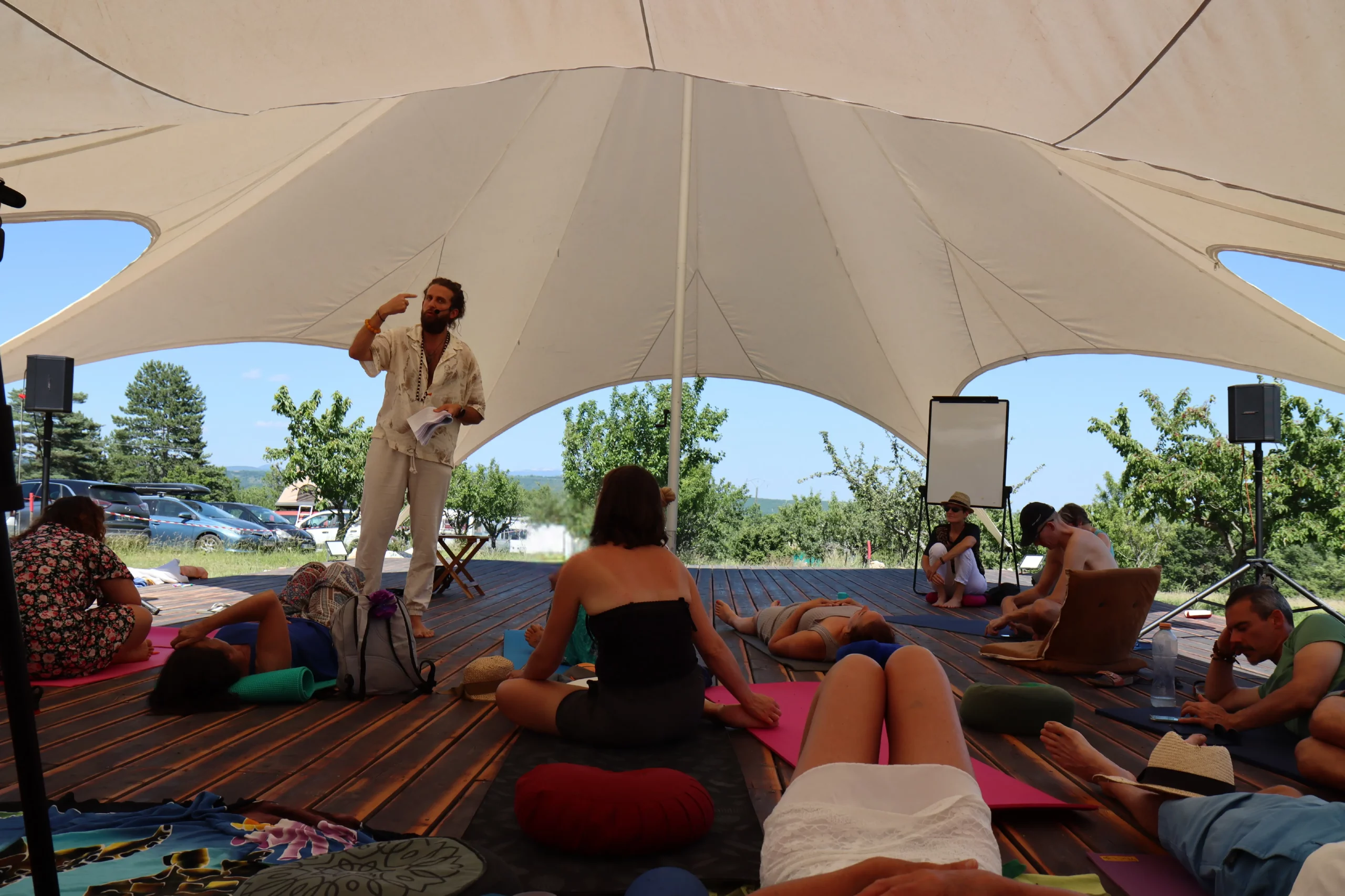 Fabio Sinicropi animant un atelier de reconnexion en pleine nature sous une grande tente, avec des participants installés sur des tapis de yoga.